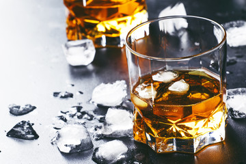 Cold whiskey with ice cubes in black table, selective focus
