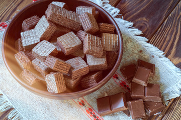 Wafers and chocolate bars on a wooden background.