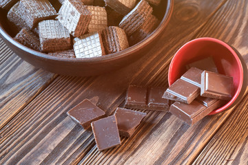 Wafers and chocolate bars on a wooden background.
