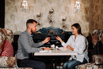 romantic relationship concept - couple with wine glasses dating and toasting in restaurant