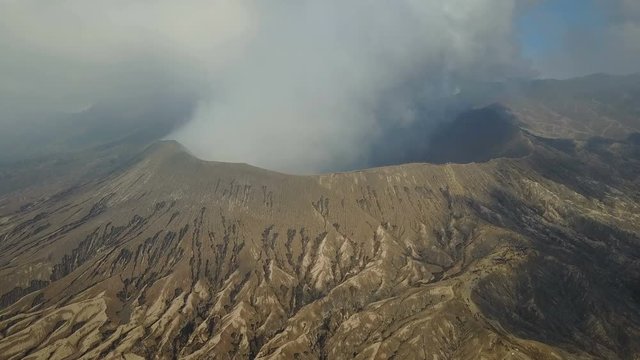 Flying towards the rim of the Mount Bromo volcano, billowing thick white grey smoke, natural scenery and tourism Indonesia