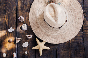 Straw hat, seashells and starfish on a wooden table