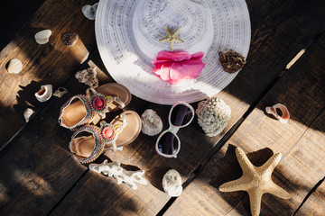 Straw hat, seashells and starfish on a wooden table