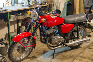 Naklejka na ściany i meble Red vintage motorcycle parked in the garage