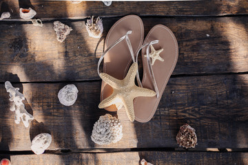 Slippers, seashells and starfish on a wooden table