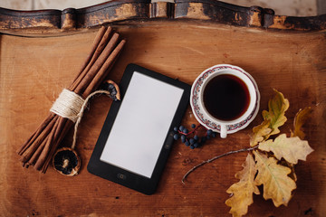 autumn leaves, e-book and cup of coffee on a wooden table