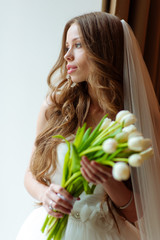 Fashion portrait. Portrait of a beautiful bride with a wedding bouquet. Blonde girl with curly hair and fashion makeup.