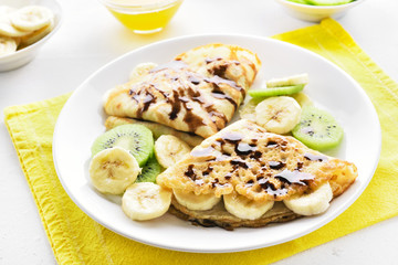 Crepes with banana, kiwi slices and chocolate sauce