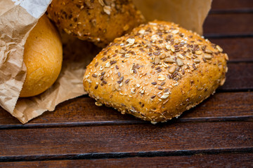 Fresh baked bread wrapped in paper, on wooden background