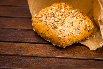 Fresh baked bread wrapped in paper, on wooden background
