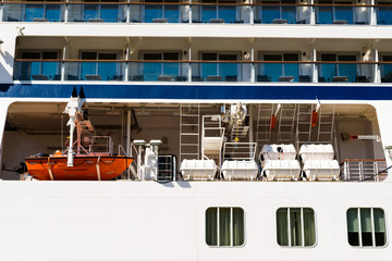 Orange lifeboat and inflatable life rafts on a white cruise ship.