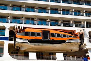Orange lifeboat on a white cruise ship.