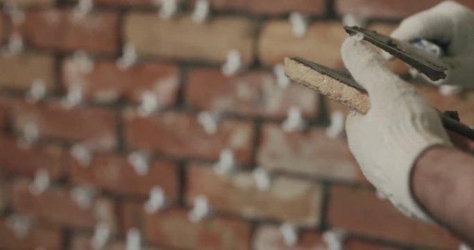 Slow motion closeup worker applying concrete glue to brick tile