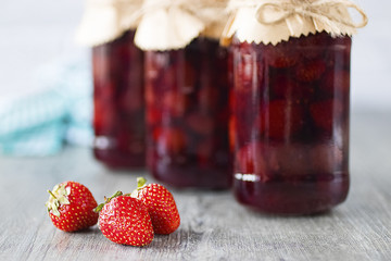 Strawberry jam in glass jar on  gray background.