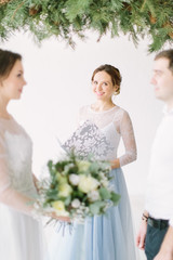 Young lovely couple with speech master of wedding ceremony against decor arch on wedding ceremony
