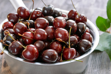 Ripe cherries in an aluminum ladle on a table