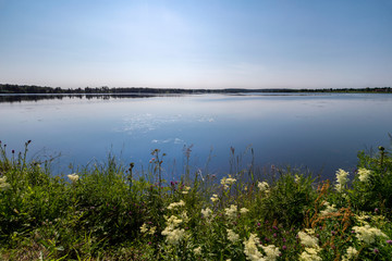 Lake with blue water and flowers on foreground