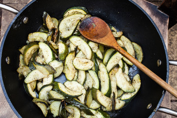 Preparation of zucchini in frying pan with hot oil. Delicious vegetables sliced and fried in oil. Vegetarian food fried in frying pan. Sliced courgette and prepared in hot oil.