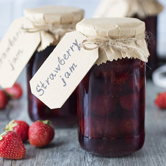 Strawberry jam in glass jar on  gray background.