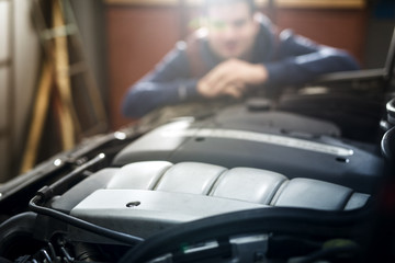 Mechanic in the workshop repairing car engine. Fixing vehicle. Automobile service and maintaining.
