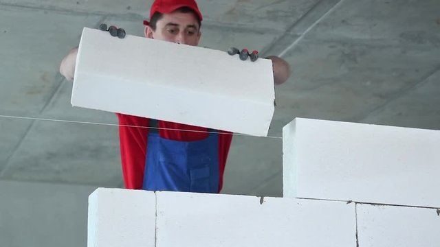 bricklayer builder working with autoclaved aerated concrete blocks. Walling
