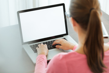 Businesswoman typing on laptop with blank screen.