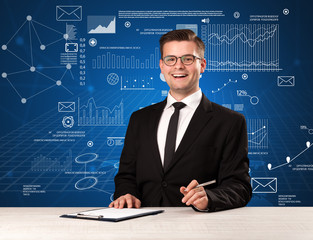 Young handsome businessman sitting at a desk with blue charts and data behind him