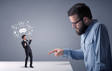 Young professional businessman being angry with an other miniature businessman who has drawn speech and thought bubbles above his head