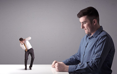 Young professional businessman being angry with an other miniature businessman in front of a...