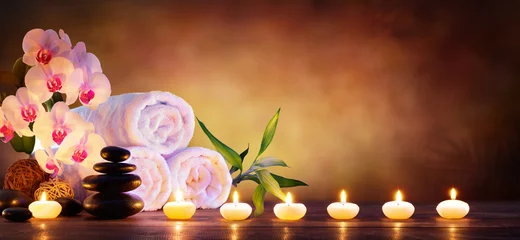 Foto auf Acrylglas Spa Spa-Konzept - Massagesteine mit Handtüchern und Kerzen im natürlichen Hintergrund