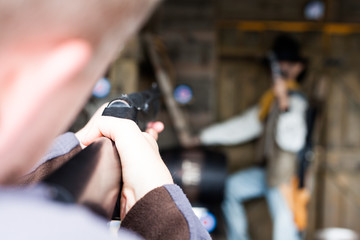 First person shooter aiming in the target. Military concept with rifle and shooting man. Practice firing with a rifle. Shooting with a rifle in a fun park.