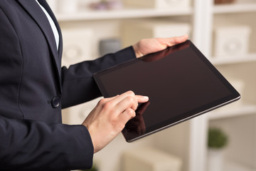 Business woman below chest using tablet in a homey environment
