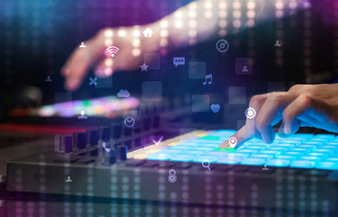 Hand mixing music on dj controller with social media concept icons
