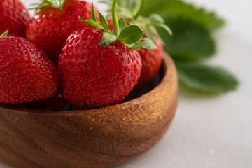 Fresh strawberries in a bowl on wooden table with low key scene.