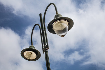 Tall old lampost with two functional bulbs. The other one is not covered and the post is painted...