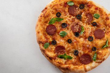 Hot pepperoni pizza on white stone background. Tasty pizza with salami, cheese and tomatoes on white table, top view