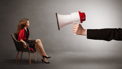 Elegant sexy model sitting opposite with a big loudspeaker

