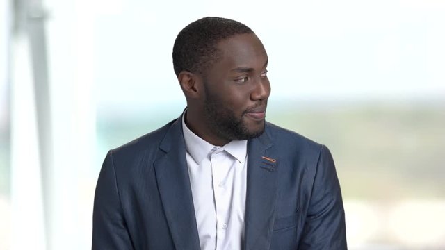Portrait of satisfied afro-american businessman. Dark-skinned macho-man looking at a girl passing by. Human facial expressions of satisfaction.