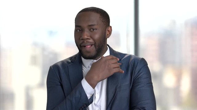 Playful sexy businessman on blurred background. Portrait of afro-american macho-man in business suit playing with lips.