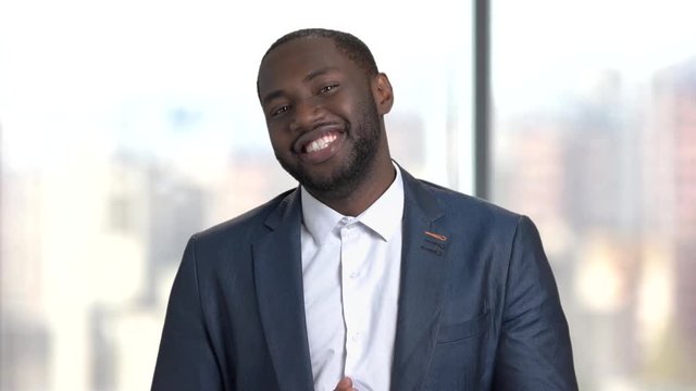 Flirtatious dark-skinned man on blurred background. Attractive afro american is man flirting and inviting somebody with finger. Handsome smiling macho-man.