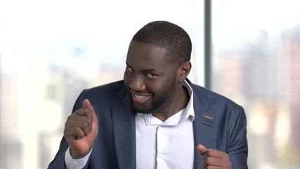 Funny dark-skinned man in formal wear. Cheerful black man in business suit inviting for a dance on blurred background. Lets dance concept.