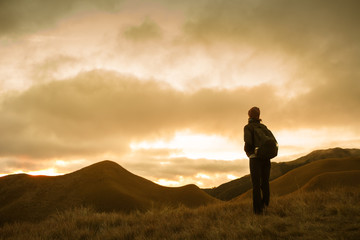 Female hiker stopping to enjoy the mountain sunset view.