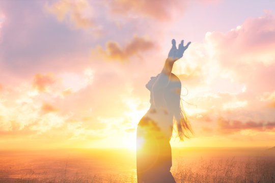 Happiness and joy.  Young female feeling free in the sunset with arms up in air. Double exposure