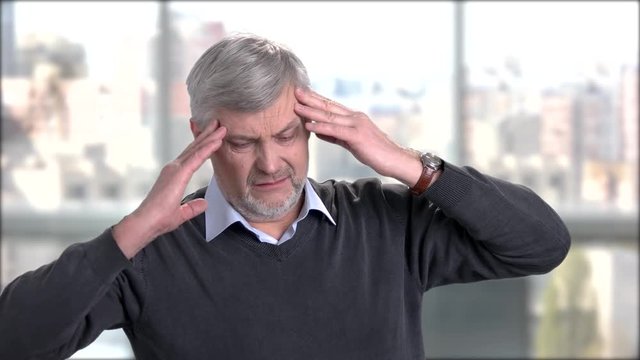 Mature man suffering from headache. Stressed senior man touching his temples because of strong head pain.