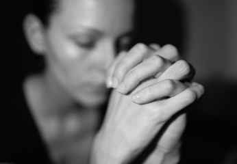 Young female praying in her bedroom.