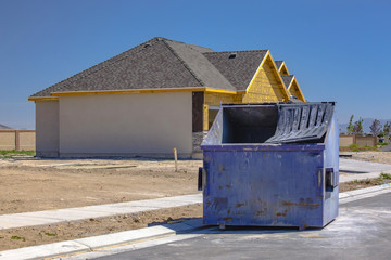 Fototapeta premium Dumpster sits outside of new construction home