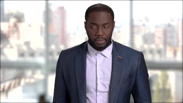 Handsome afro-american businessman checking time on watch. Confident afro-american entrepreneur looking at his wrist watch on blurred background. Waiting for business partner. Time is money concept.