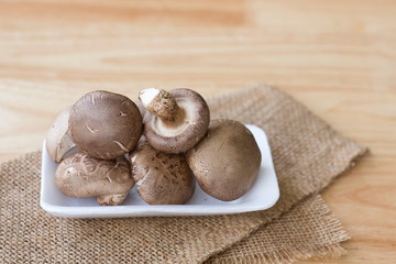 Shiitake mushroom on white plate on wooden table.