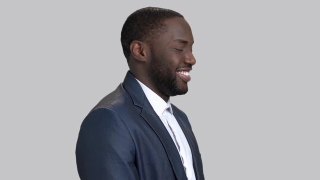 Joyful afro-american businessman on grey background. Smiling dark-skinned man in business suit.