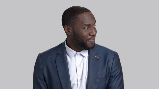Face of playful businessman looking on girl. Hot dark-skinned macho-man on grey background.